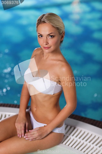 Image of happy woman sitting in jacuzzi at poolside