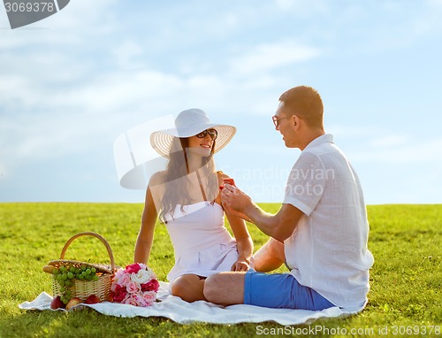 Image of smiling couple with small red gift box on picnic