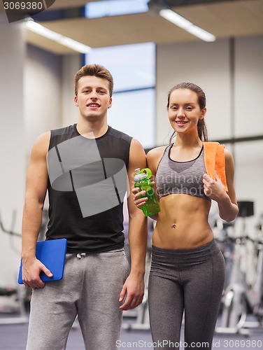 Image of happy couple in gym with water and tablet pc