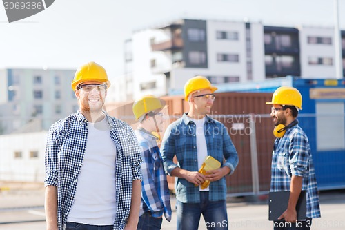 Image of group of smiling builders in hardhats outdoors