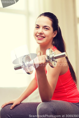 Image of smiling girl exercising with dumbbells