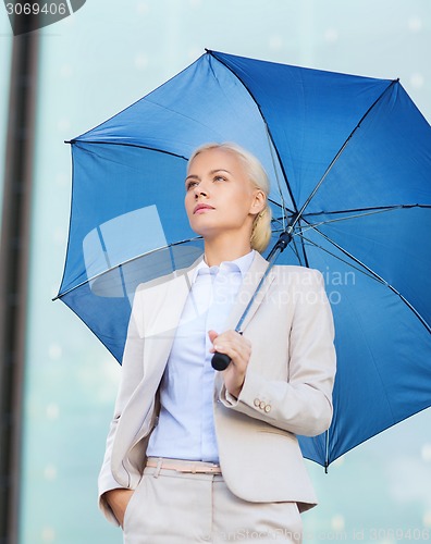 Image of young serious businesswoman with umbrella outdoors