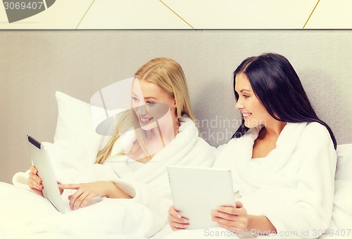 Image of girlfriends with tablet pc computers in bed