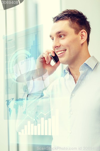 Image of smiling businessman with smartphone in office