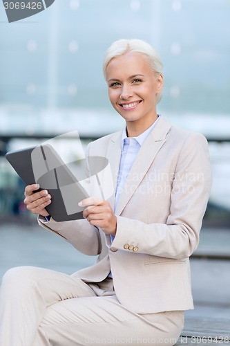 Image of smiling businesswoman with tablet pc outdoors