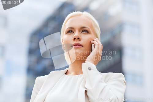 Image of serious businesswoman with smartphone outdoors