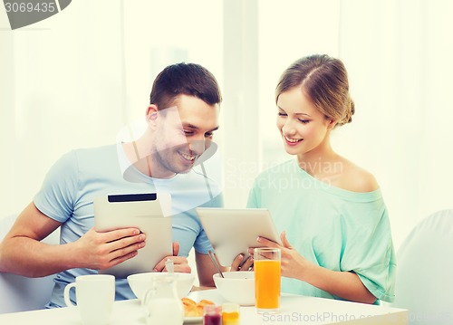 Image of smiling couple with tablet pc reading news