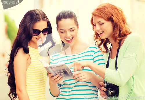 Image of smiling teenage girls with city guide and camera