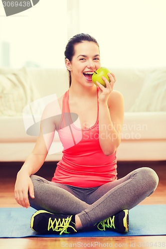 Image of smiling teenage girl with green apple at home