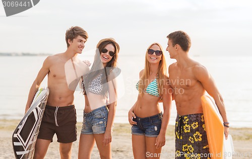 Image of smiling friends in sunglasses with surfs on beach