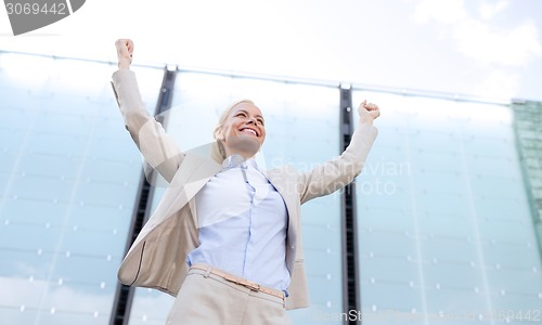 Image of young smiling businesswoman over office building