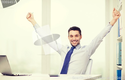 Image of smiling businessman with laptop and documents