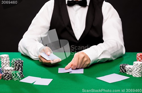 Image of holdem dealer with playing cards and casino chips