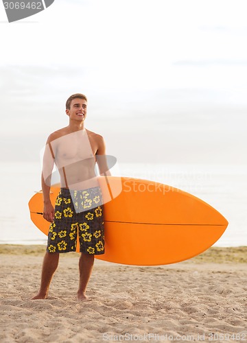 Image of smiling young man with surfboard on beach