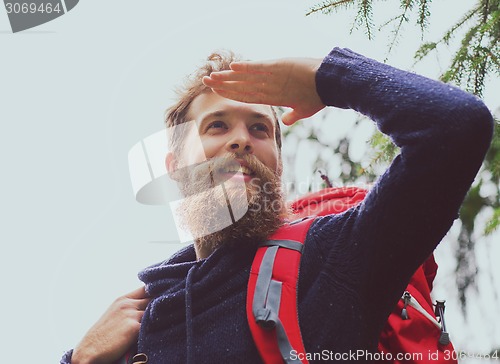 Image of smiling man with beard and backpack hiking