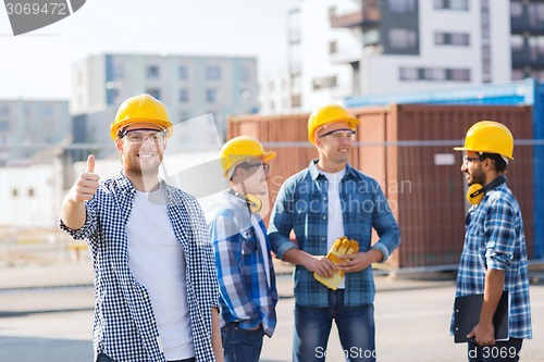 Image of group of smiling builders in hardhats outdoors