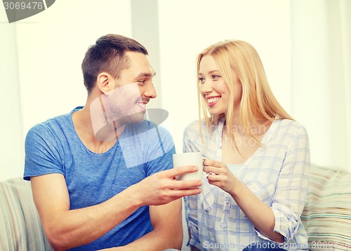 Image of smiling man giving cup of tea or coffee to wife