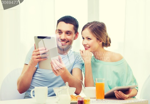 Image of smiling couple with tablet pc reading news