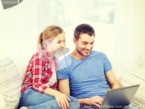 Image of smiling couple with laptop computer at home