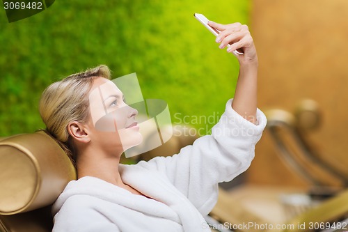 Image of beautiful young woman with smartphone at spa