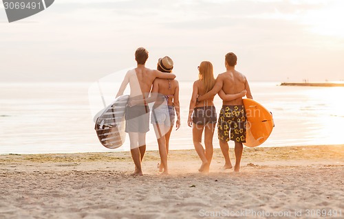 Image of smiling friends in sunglasses with surfs on beach
