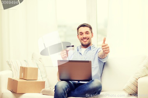 Image of man with laptop, credit card and cardboard boxes