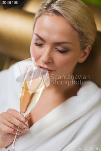 Image of beautiful young woman drinking champagne at spa