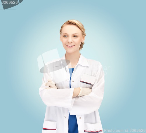 Image of smiling young female doctor over blue background