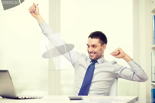 Image of smiling businessman with laptop and documents