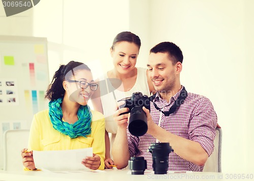 Image of smiling team with photocamera working in office