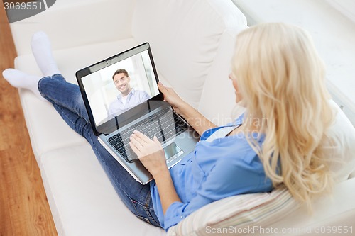 Image of smiling woman with laptop computer at home