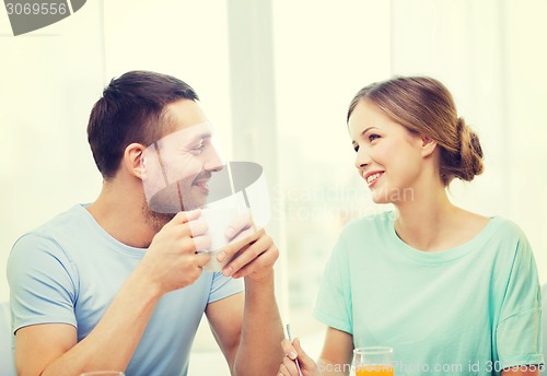 Image of smiling couple having breakfast at home