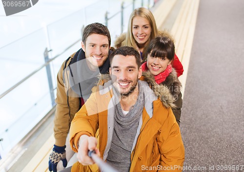 Image of happy friends taking selfie on skating rink