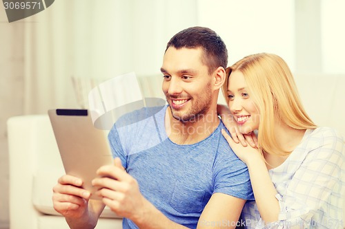 Image of smiling happy couple with tablet pc at home