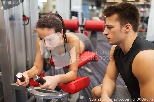 Image of young woman with trainer exercising on gym machine