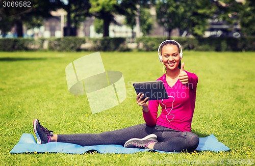 Image of smiling woman with tablet pc outdoors