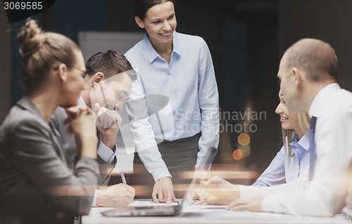 Image of smiling female boss talking to business team