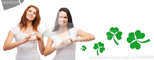 Image of smiling girls showing heart gesture with shamrock