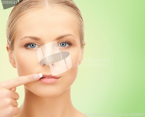 Image of beautiful young woman pointing finger to her lips