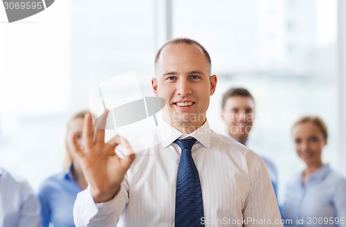Image of smiling businessman showing ok sign in office