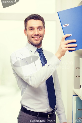 Image of handsome businessman picking folder at office