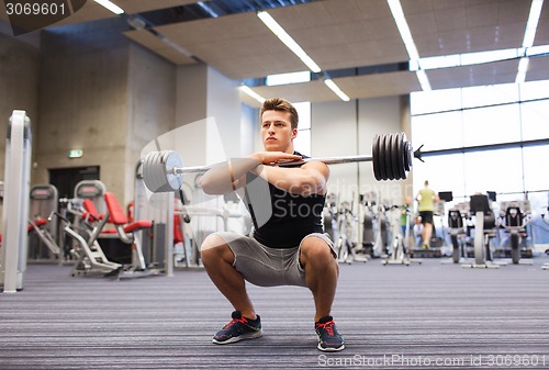 Image of young man flexing muscles with barbell in gym