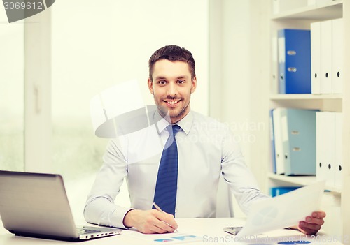 Image of smiling businessman with laptop and documents