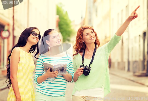 Image of smiling teenage girls with city guide and camera