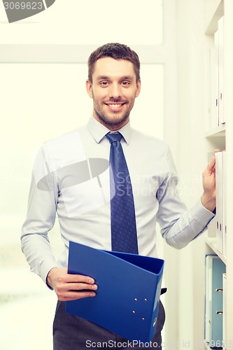 Image of handsome businessman picking folder at office