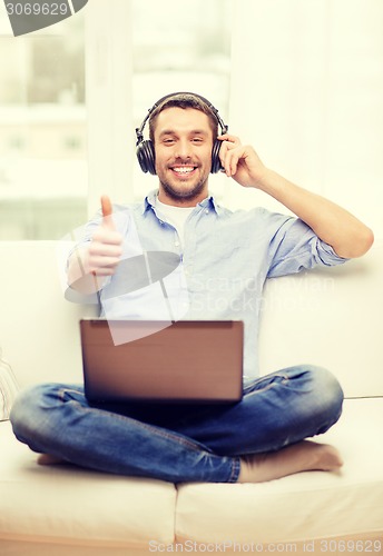 Image of smiling man with laptop and headphones at home