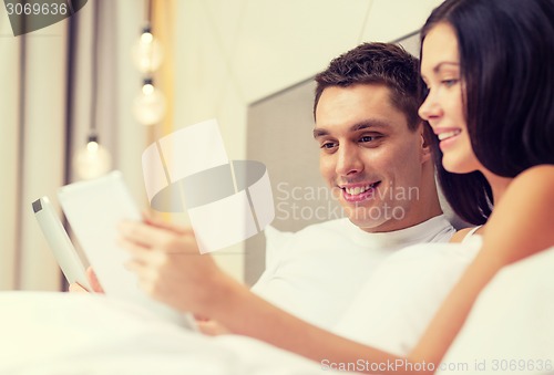 Image of smiling couple in bed with tablet pc computers