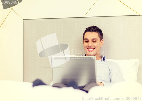 Image of happy businesswoman with laptop in hotel room