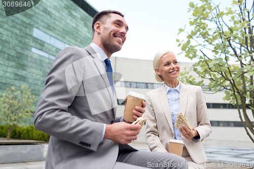 Image of smiling businessmen with paper cups outdoors