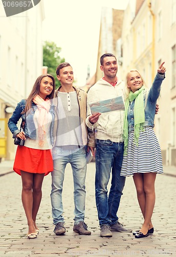 Image of group of smiling friends with map and photocamera